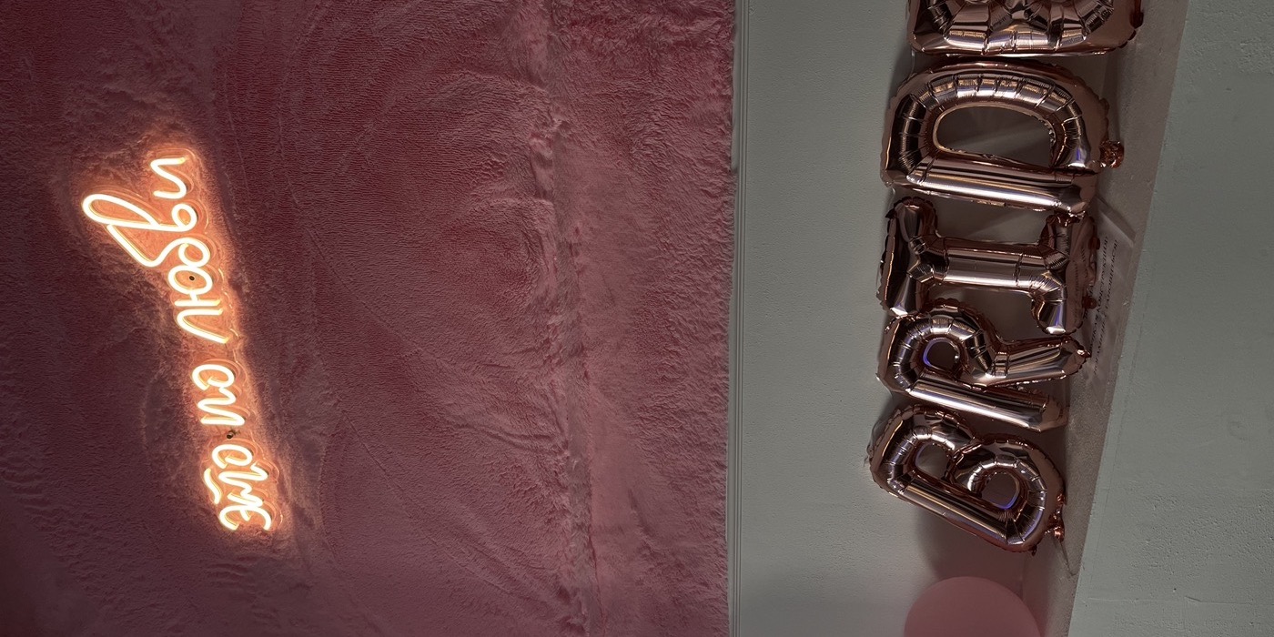 Лаунж-зона с угловым диваном, окнами и неоновой вывеской «это по любви»